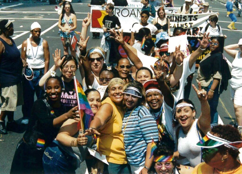 A group of people celebrating a Pride and protesting for housing equality.