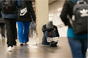 Una persona pide dinero con un cartel en una estación de metro de Nueva York, el lunes 21 de febrero de 2022. (Foto AP/Seth Wenig)