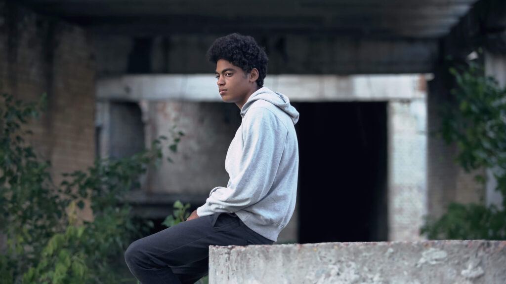 A person sits on their own in an outdoor concrete setting.