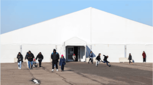 Migrants families walk around the shelters at Floyd Bennett Field in the Brooklyn borough of New York on in February 2024. Photographer: Charly Triballeau/AFP/Getty Images (Charly Triballeau/AFP/Photographer: Charly Triballeau/)